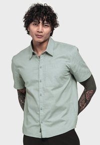 Kurzarmhemd in Hellgrün, aus weichem Stoff, mit Knopfleiste, Brusttasche und subtiler Logo-Stickerei.