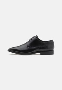 Pantofi de dress pentru bărbați din piele neagră, cu vârf ascuțit, închidere cu șireturi și toc mic, pe fundal alb.