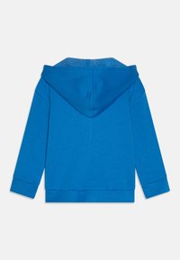 Sweatshirt azul com uma textura suave, apresentando uma capucha grande, mangas longas e punhos e barra canelados, desenhado com uma cor sólida.