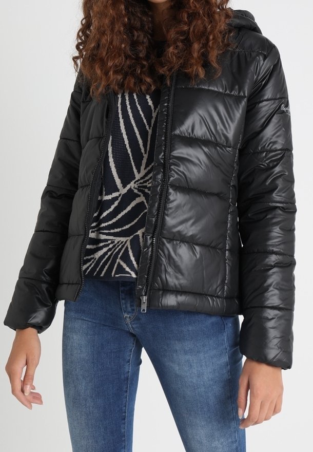 Sort dunjakke med hætte, der har et skinnende, quiltet design, forreste lynlås og elastiske ærmekanter. Båret over en mønstret sweater.