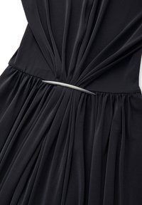 Czarna plisowana sukienka z gładkim, metalicznym srebrnym paskiem. Tkanina ma miękką teksturę, tworząc zwiewną sylwetkę z detalami w formie marszczeń.