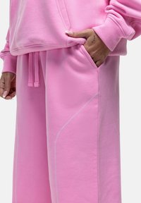 Roze sweater en sweatpants set in zachte stof, met een trekkoord, zakken en contrasterende stiksel details.