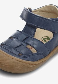 Námořnické modré kožené sandály s designem křížových pásků, nastavitelného suchého zipu a hnědé gumové podrážky s texturovaným gripem.