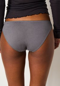 Slip in cotone grigio con una superficie liscia e una veste a vita bassa. Presenta bordi cuciti e un design senza cuciture per un maggiore comfort.