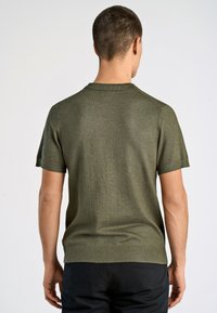 Zielony krótki sweter z dzianiny z okrągłym dekoltem. Charakteryzuje się gładką fakturą i dopasowanym krojem, podkreślając minimalistyczny design.