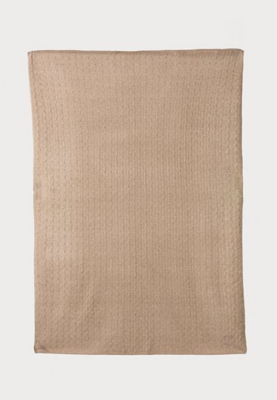 Beige, teksturoitu peitto, jossa on ribbeerattu kuosi, suorakulmainen muoto ja viimeistellyt reunat. Pehmeä kangas, joka soveltuu lämpöön ja mukavuuteen.
