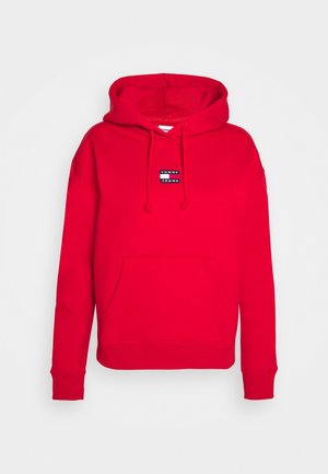 Roter Hoodie mit vorderer Bauchtasche, verstellbarer Kordelkapuze, gerippten Bündchen und Saum sowie kleinem "Tommy Jeans"-Logo auf der Brust.