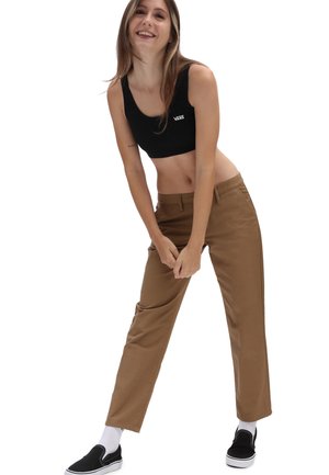 Schwarzes Crop-Top, braune gerade geschnittene Hose, Baumwollmaterial, minimalistisches Design. Schwarze Slipper mit weißen Sohlen und Socken in Crew-Länge.