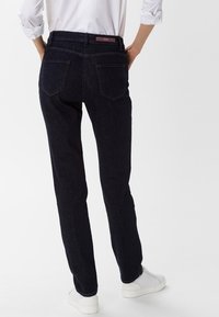 Tmavě modré džíny typu denim se střihem rovné nohavice, obsahující dvě zadní kapsy, jemné prošívání a středně vysoký pás.