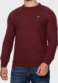 Weinroter Strickpullover mit strukturiertem Muster, Rundhalsausschnitt und gerippten Bündchen. Verfügt über ein kleines gelbes Logo auf der Brust.