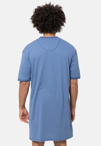 T-shirt oversize a strisce blu con maniche corte, scollo rotondo e tessuto morbido. Linee orizzontali di diverse larghezze creano un motivo sottile.