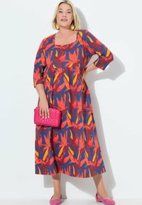 Kukkakuvioinen mekko, jossa on kolmannelta neljännekseltä hihat, neliön muotoinen kaula-aukko ja kerätty vyötärö punaisena, oranssina ja sinisenä. Yhdistetty vaaleanpunaisen clutchin ja kenkien kanssa.