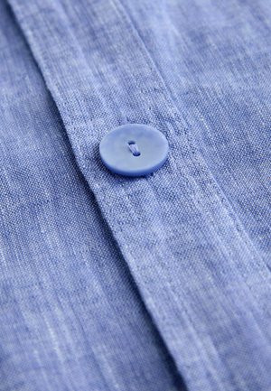 Tissu de chemise en lin bleu clair avec une texture lisse, doté d'un bouton en plastique et de coutures détaillées le long du pied de col.