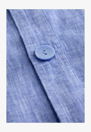 Tissu de chemise en lin bleu clair avec une texture lisse, doté d'un bouton en plastique et de coutures détaillées le long du pied de col.