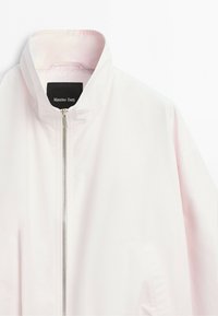 White lightweight jacket with stand-up collar and front silver zipper, brand label inside collar reading Massimo Dutti.
