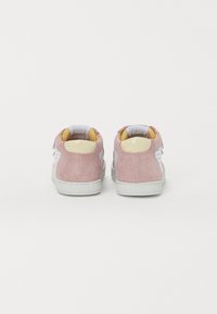 Sneaker in suede rosa con accenti bianchi, punta rotonda, suola in gomma e fodera gialla imbottita. Presenta dettagli perforati sui lati.