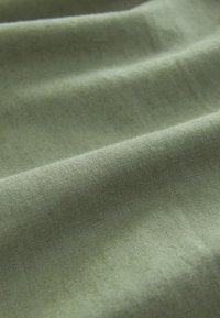 Lysegrønt stof med en glat tekstur, der har subtile folder og en ensartet finish, velegnet til forskellige anvendelser.