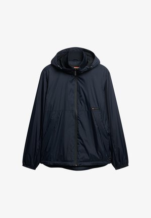 Jachetă de tip windbreaker de culoare bleumarin, cu glugă, fermoar frontal, manșete elastice și tiv drept. Fabricată dintr-un material ușor, rezistent la apă.