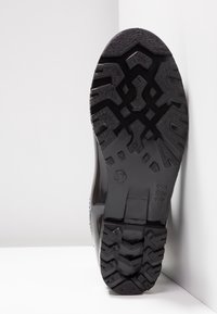 Suela de bota de goma negra con un patrón de textura, detalles moldeados y un tamaño marcado de 37; diseñada para tracción y durabilidad.