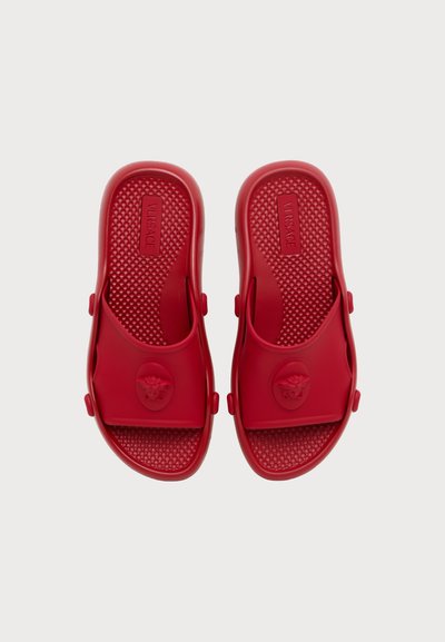 Paire de sandales rouges à enfiler avec semelles texturées et logo tête de Méduse embossé sur les brides, étiquetées Versace à l'intérieur.