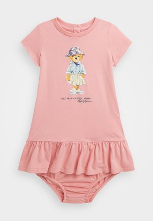 Robe bébé rose à manches courtes avec ourlet froufroutant et un ours en peluche portant un chapeau et une jupe imprimés sur le devant, avec le texte "Polo Bear by Ralph Lauren".