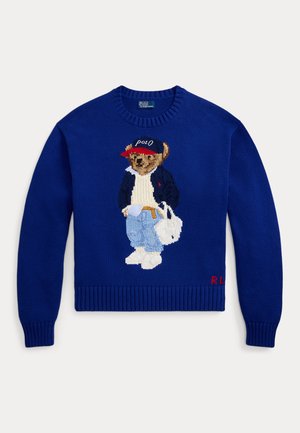 Maglione blu lavorato a maglia con un orso ricamato che indossa una giacca e jeans, scarpe bianche e un berretto rosso, con "R.L." ricamato sull'orlo.