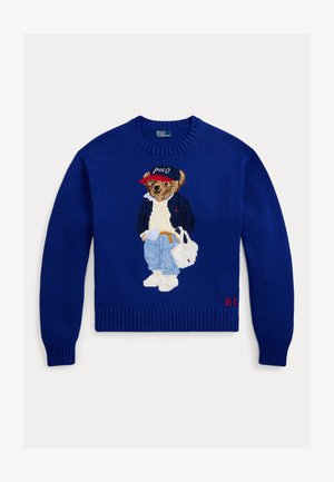 Maglione blu lavorato a maglia con un orso ricamato che indossa una giacca e jeans, scarpe bianche e un berretto rosso, con "R.L." ricamato sull'orlo.