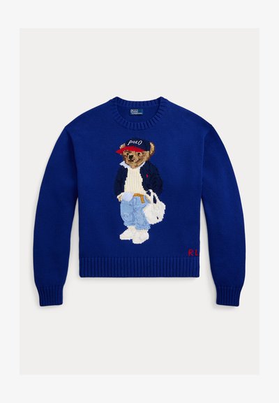 Μπλε πλεκτό πουλόβερ με κεντημένη αρκούδα που φοράει σακάκι και τζιν, λευκά παπούτσια και κόκκινο καπέλο, με το «R.L.» κεντημένο στο στρίφωμα.