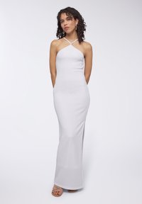 Abito maxi bianco aderente con tessuto testurizzato, dotato di collo a halter incrociato e uno spacco alto sulla coscia da un lato.