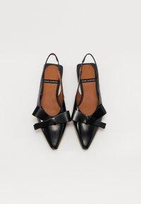 Zapatos de charol negros tipo slingback con punta afilada, que cuentan con un ancho lazo decorativo y una plantilla color marrón. Textura suave con un hardware mínimo.