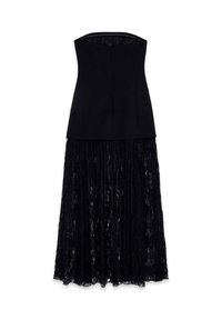 Juoda suknelė be petnešų, su prigludusia viršutine dalimi ir ilga nėrinių sijonu, kuris nusileidžia žemiau kelių, pateikta ant balto fono.