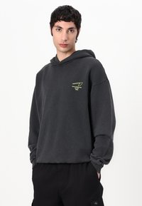 Dark gray hoodie with a relaxed fit, adjustable hood, and a neon green logo on the chest. Cotton material with soft texture.