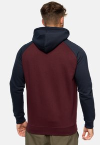 Sudadera con capucha que presenta un cuerpo burdeos y mangas raglán azul marino. Fabricada con una tela suave y con puños y dobladillo de canalé.