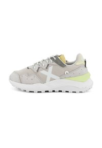 Scarpa sportiva grigia e bianca realizzata in materiali mesh e suede, con un accento verde sul tallone e una suola bianca a fantasia. Presenta lacci riflettenti.