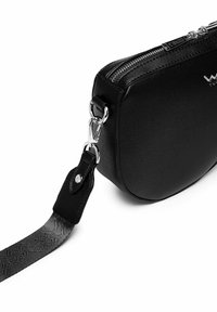 Černá kožená crossbody taška se stříbrnými detaily, zipovým uzávěrem a texturovaným popruhem. Zaoblený tvar s hladkým povrchem.