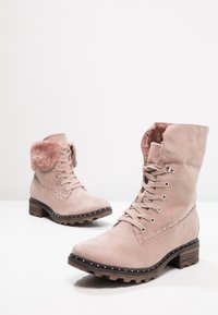 Bottines en daim rose avec manchette en fausse fourrure, bout rond et lacets à l'avant. Comprend des accents de rivets argentés et un talon bloc en bois solide.