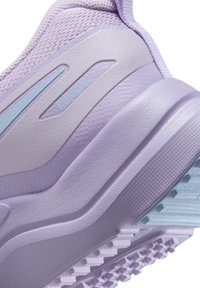 Chaussure de course en lavande claire avec un matériau supérieur texturé, des accents en plastique lisse et une semelle à motif en bleu pâle.