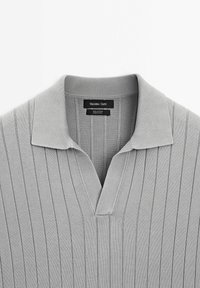 Gray cotton polo shirt featuring a flat collar, v-neck design, and vertical ribbed texture. Label reads "Massimo Dutti."