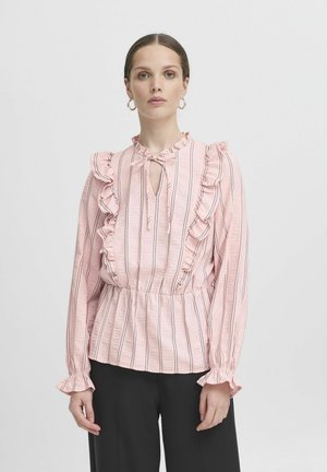 Lichtroze blouse met ruches, keyhole hals en verticale strepen. Lange mouwen met elastische manchetten, textiele stof. Zwarte broek.