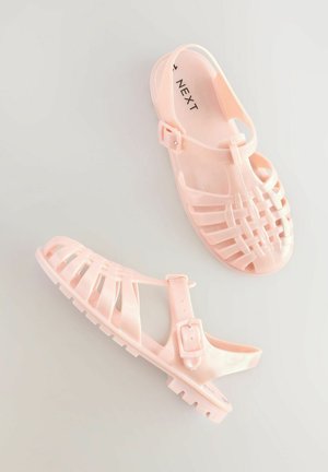Chanclas de plástico rosa con un acabado translúcido, que presentan un diseño de tiras, hebilla ajustable y suela texturizada para mayor agarre.
