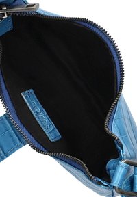 Blauw krokodillenpatroon tasinterieur met zwarte stofvoering. Heeft een ritssluiting en een klein merklabel aan de binnenkant.