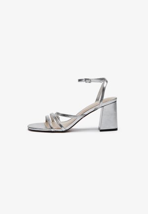 Silver metallic high-heeled sandal with a block heel, thin ankle strap, and multiple wide straps across the forefoot. Smooth texture.
