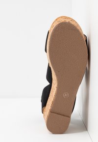 Sandale compensée avec plateforme en liège et semelle en caoutchouc texturée, dessus en tissu noir, taille 37 visible sur la semelle, positionnée sur un fond blanc.