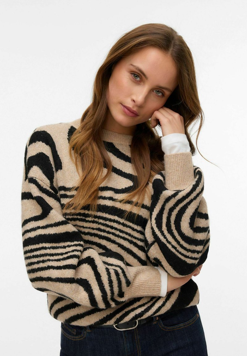 Béžový svetr s černými zebřími pruhy, kulatým výstřihem a volnými rukávy. Texturovaná pletenina s bílými akcenty na manžetách. Ležérní design.