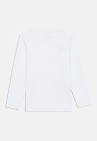 Biała bawełniana koszulka z długim rękawem, z okrągłym dekoltem i minimalistycznym wzorem. Na plecach brak widocznych logo lub wzorów.