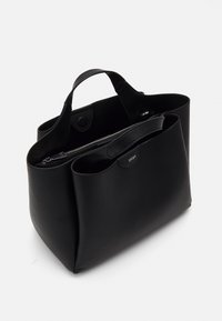Svart skinn tote-veske med teksturert overflate, doble håndtak и en glidelåslomme, med en subtil logo-detalj.