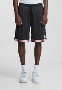 Pantalones cortos deportivos negros con acentos en rayas rojas y blancas, cintura elástica con cordón y un logo en la parte inferior de la pierna derecha.