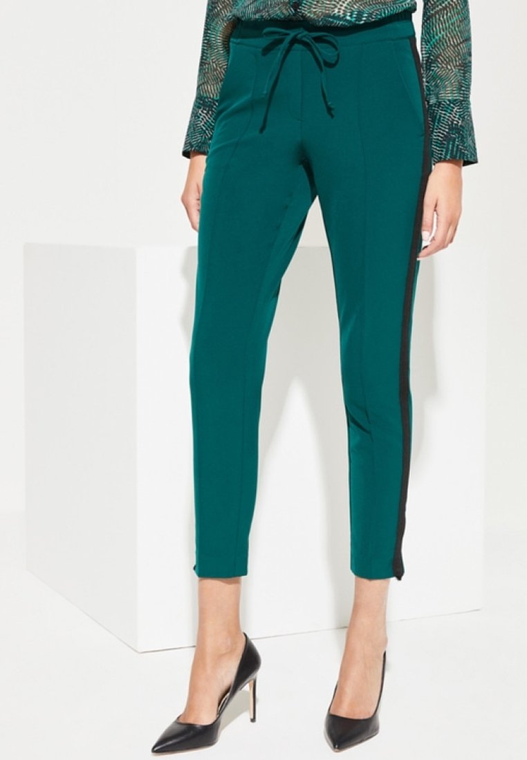 Teal tapering broek met een drawstring taille, zijden zwarte strepen en een fijne textuur. Gecombineerd met zwarte hoge hakken en een gestreept topje.