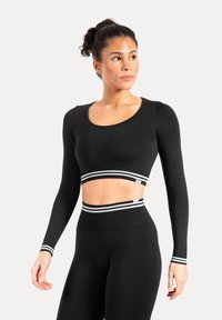 Sort cropped top med lange ærmer, der har en rund halsudskæring og horisontale hvide og grå striber ved kanten. Glat, elastisk stof.