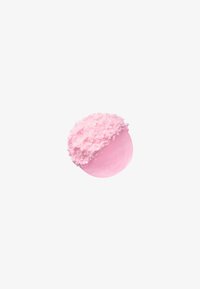 Confiserie ronde rose, à moitié recouverte de flocons de noix de coco roses duveteux et texturés sur fond blanc.